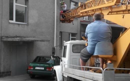 мужчина на автовышке возле окон родддома